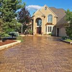 Luxury house with wide stamped concrete driveway and green landscaping