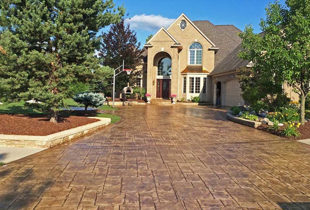Luxury house with wide stamped concrete driveway and green landscaping